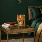 lit gold leaf candle holder on bedside table