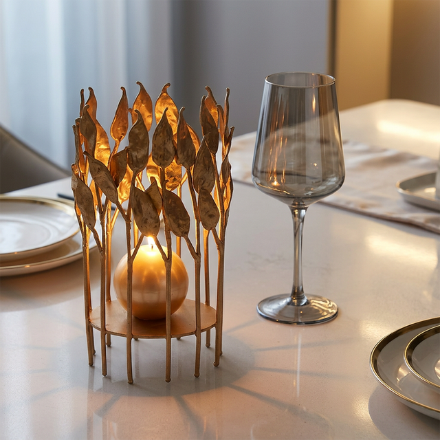lit gold leaf candle holder on dining table with wine glass