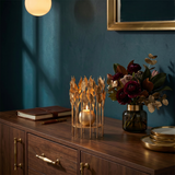 lit gold leaf candle holder on wooden cabinet