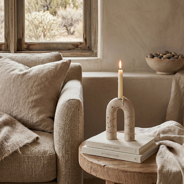 lit stone arch candle holder on side table