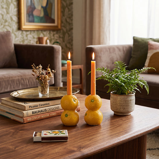 orange candle holders behind stacked books