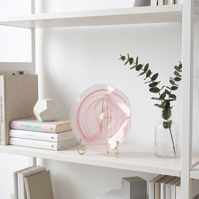 pink round glass decorative plate on white bookshelf
