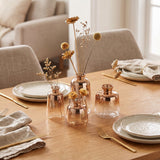 rose gold vases with dried flowers on wooden table