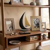 sailboat sculpture on wooden shelf with frames