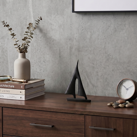 sailboat sculpture with plant on wooden cabinet
