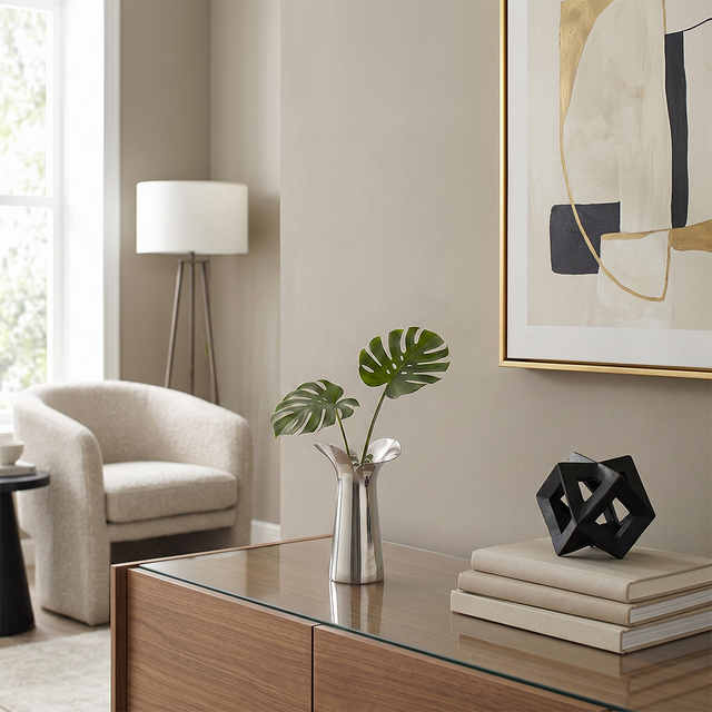 silver vase with monstera on wooden cabinet