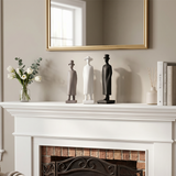 three figurines with top hats on fireplace mantel