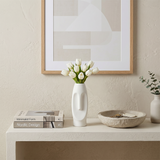 white face vase with tulips on white console
