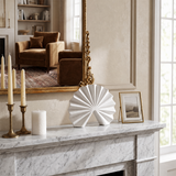 white fan sculpture on marble mantel with candles
