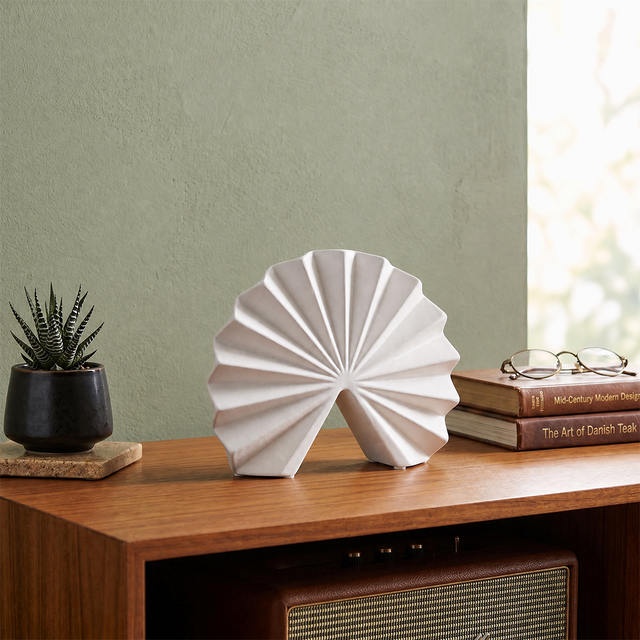 white fan sculpture on wooden cabinet with books