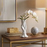 white hand vase with orchid on gold console