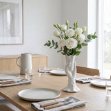 white hand vase with white roses on dining table