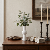 white ribbed vase with eucalyptus on wooden buffet