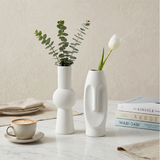 white vases with flowers on marble table with books