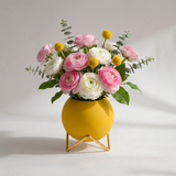 yellow spherical vase with pink flowers on white